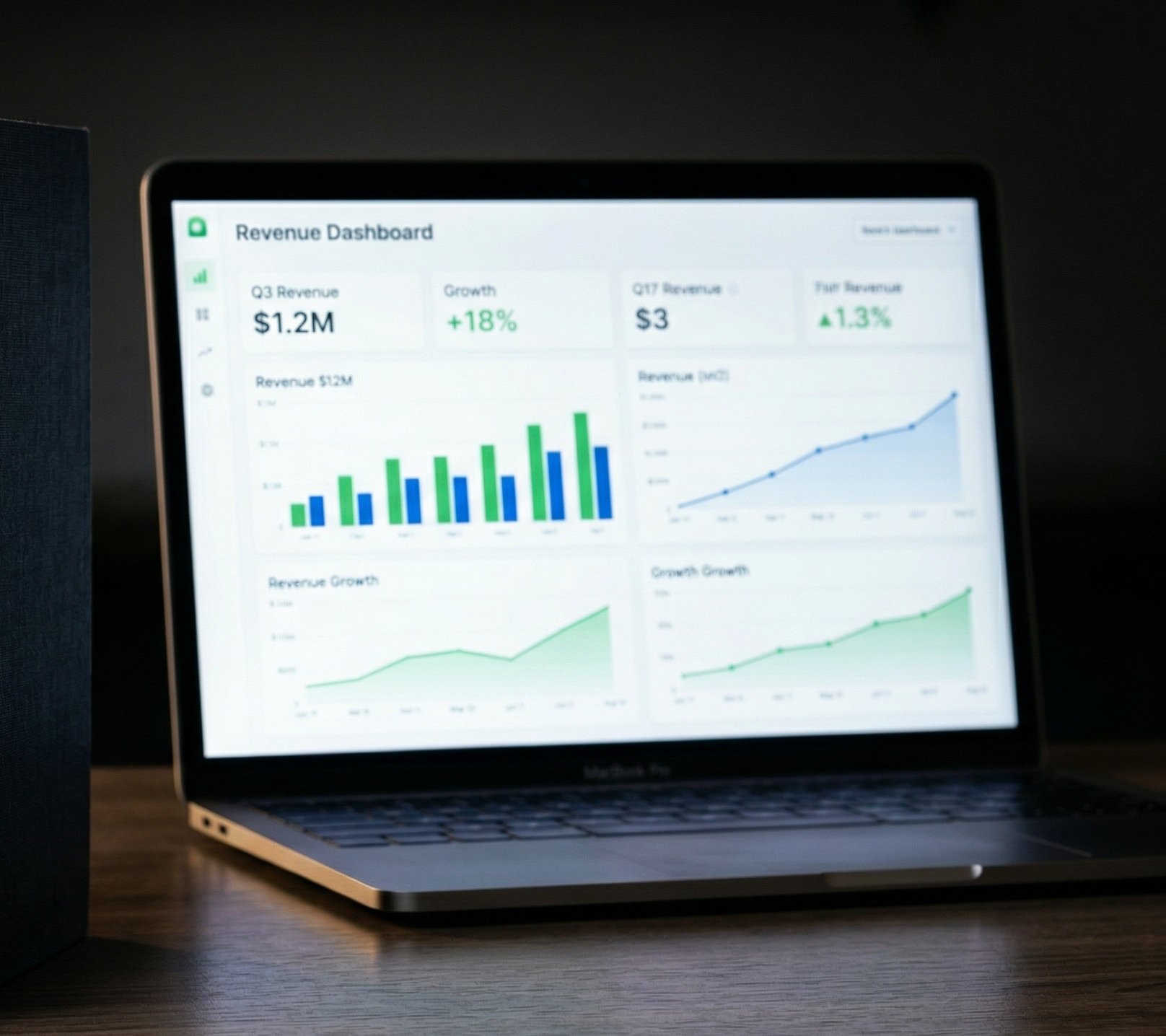 Two books on a dark wood desk with a laptop showing a revenue dashboard